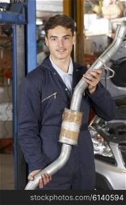 Apprentice Mechanic Holding Exhaust Pipe In Auto Repair Shop