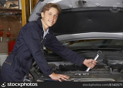 Apprentice Mechanic In Auto Shop Working On Car Engine