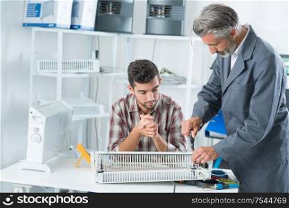 apprentice repairing appliance with his mentor