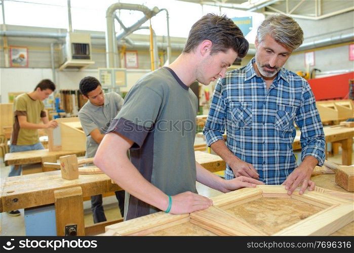 apprentices and teacher with wood frame