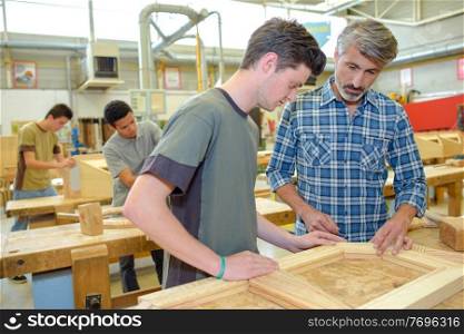 apprentices and teacher with wood frame