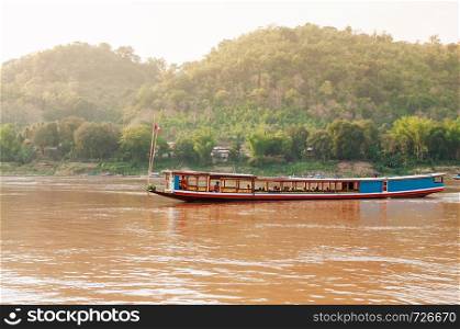 APR 3,2018 Luang Prabang, Laos - Vintage colourful wooden boats in yellow Mekong river during summer with soft evening light