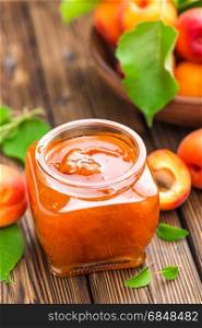 Apricot jam in a jar and fresh fruits with leaves