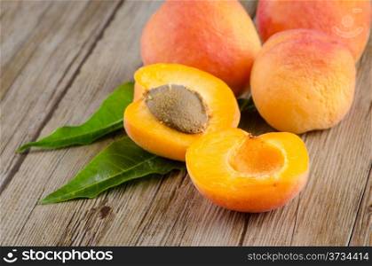 Apricots with leaves on the wooden table.
