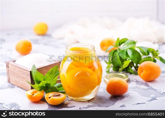 apricots with sirup in glass bank and on a table