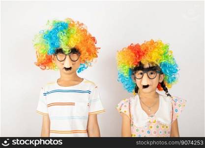 April Fool&rsquo;s Day. Two brothers funny kid boy and little girl clown wears curly wig colorful big nos and glasses and has mustache isolated on white background, Happy children festive decor