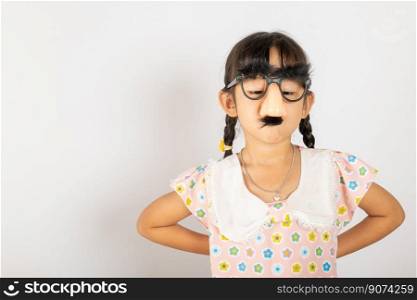 April Fool’s Day. Portrait of Funny kid little girl clown wears a big nos and glasses and has a mustache isolated on white background with copy space, Happy smile child festive decor