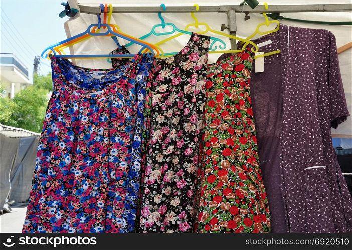 Apron smock dress overalls and robes on hangers at outdoors street market. Old fashioned womens summer clothes.
