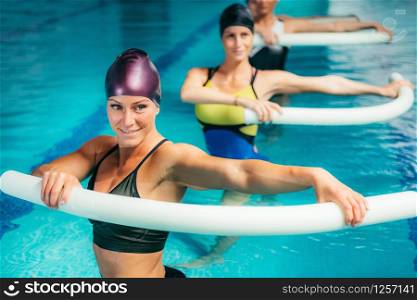 Aqua Aerobic Training with Water Fitness Equipment. Women Training with Swimming Noodles.. Aqua Aerobic Training in Water Sport Centre.
