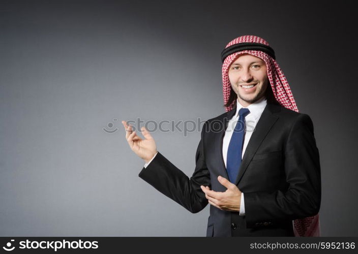 Arab businessman pointing to something or somebody against grey background