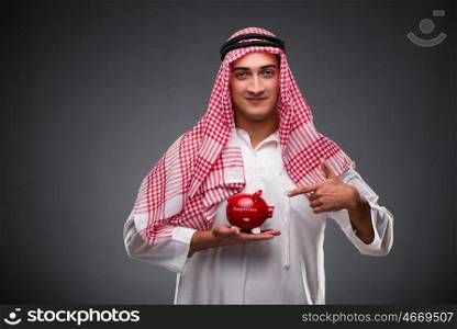 Arab businessman with piggybank on gray background