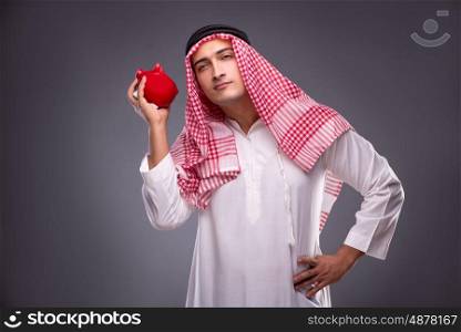 Arab businessman with piggybank on gray background