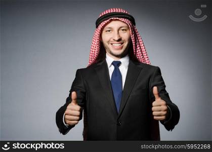 Arab businessman with thumbs up againt grey background