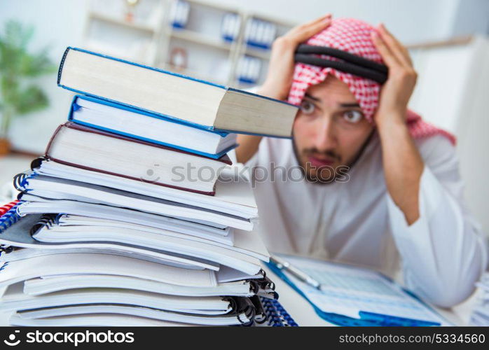 Arab businessman working in the office doing paperwork with a pi. Arab businessman working in the office doing paperwork with a pile of papers