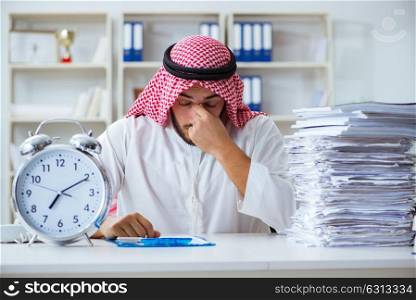 Arab businessman working in the office doing paperwork with a pi. Arab businessman working in the office doing paperwork with a pile of papers