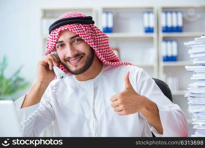 Arab businessman working in the office doing paperwork with a pi. Arab businessman working in the office doing paperwork with a pile of papers