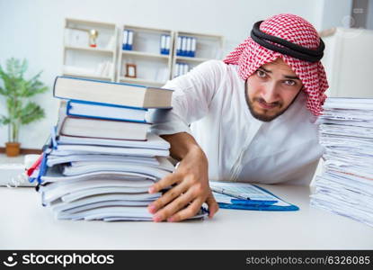 Arab businessman working in the office doing paperwork with a pi. Arab businessman working in the office doing paperwork with a pile of papers