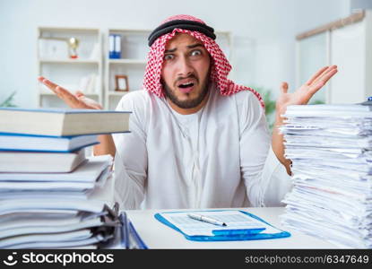 Arab businessman working in the office doing paperwork with a pi. Arab businessman working in the office doing paperwork with a pile of papers