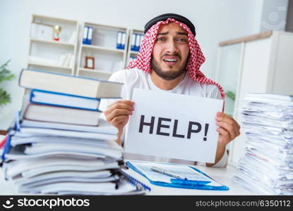 Arab businessman working in the office doing paperwork with a pi. Arab businessman working in the office doing paperwork with a pile of papers