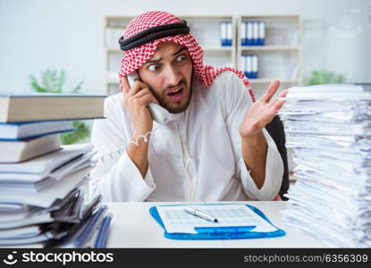 Arab businessman working in the office doing paperwork with a pi. Arab businessman working in the office doing paperwork with a pile of papers