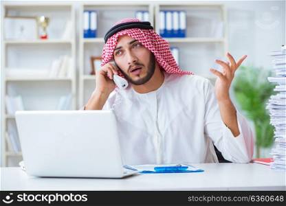 Arab businessman working in the office doing paperwork with a pi. Arab businessman working in the office doing paperwork with a pile of papers