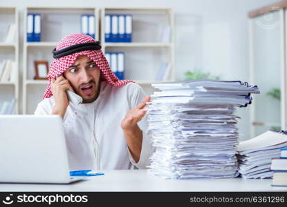 Arab businessman working in the office doing paperwork with a pi. Arab businessman working in the office doing paperwork with a pile of papers