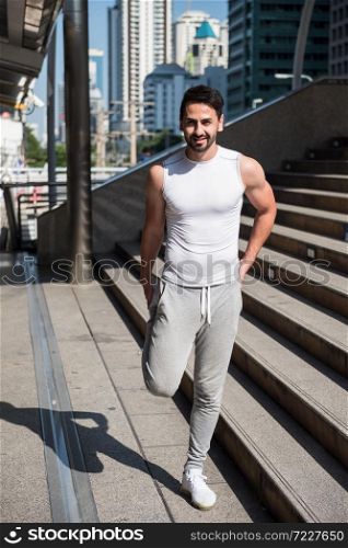 Arab handsome beard man stretching foot and leg on stair before jogging or running in city.. Sport and healthy lifestyle with social distancing during covid-19 or coronavirus.