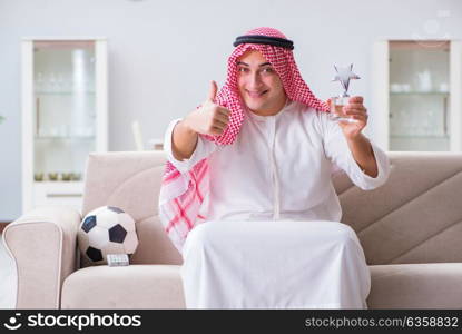 Arab man watching sport football at tv