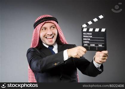 Arab man with movie clapper against grey background