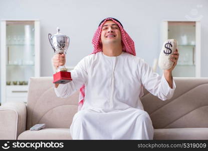 Arab man with prize and money on sofa