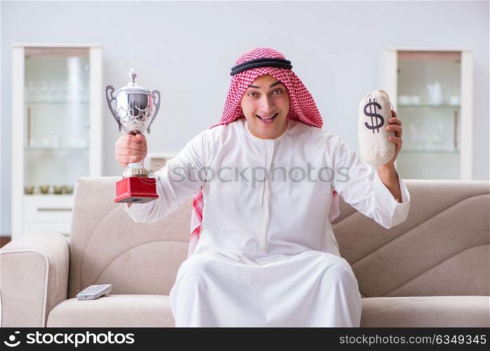 Arab man with prize and money on sofa