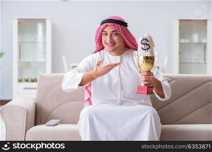 Arab man with prize and money on sofa
