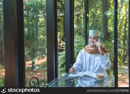 Arab muslim businessman use smartphone communication and write on book in coffee shop ,freelance no working space lifestyle.