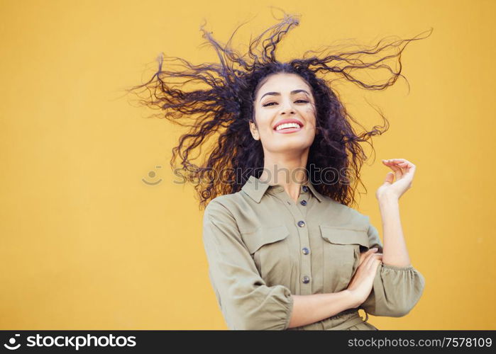 Arab woman with curly hair moved by the wind in urban background. Arab woman with curly hair moved by the wind