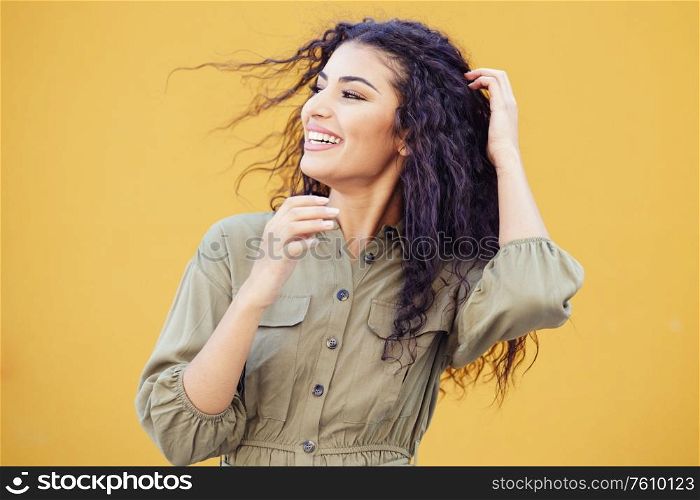 Arab woman with curly hair moved by the wind in urban background. Arab woman with curly hair moved by the wind