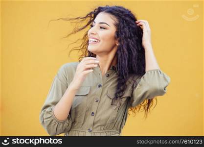 Arab woman with curly hair moved by the wind in urban background. Arab woman with curly hair moved by the wind