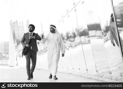 arabian business people walking in front of modern corporate building