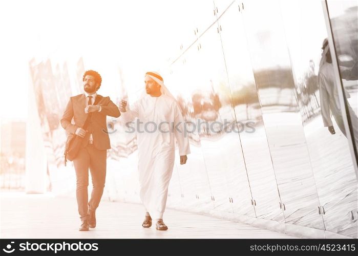 arabian business people walking in front of modern corporate building