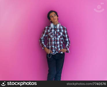 Arabic Teenage Boy Wearing Headphones And Listening To Music pink background. High quality photo. Arabic Teenage Boy Wearing Headphones And Listening To Music pink background