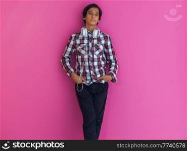 Arabic Teenage Boy Wearing Headphones And Listening To Music pink background. High quality photo. Arabic Teenage Boy Wearing Headphones And Listening To Music pink background