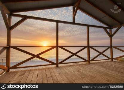 Arbour on the sea shore on the beach at sunset. Nature and indoor composition.