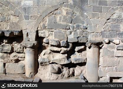 Arc, stone wall and columns on the street of Bosra in Syria