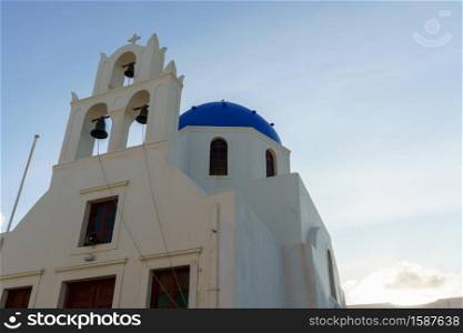 Arch with a bell, white church with blue domes in Oia, Santorini, Greece.