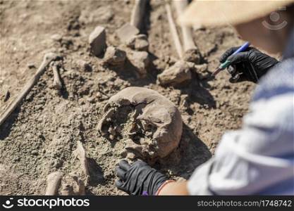 Archaeological excavations. Female archaeologist with tools conducting research on ancient human bones.. Ancient Burial Site- Archaeological Excavations 