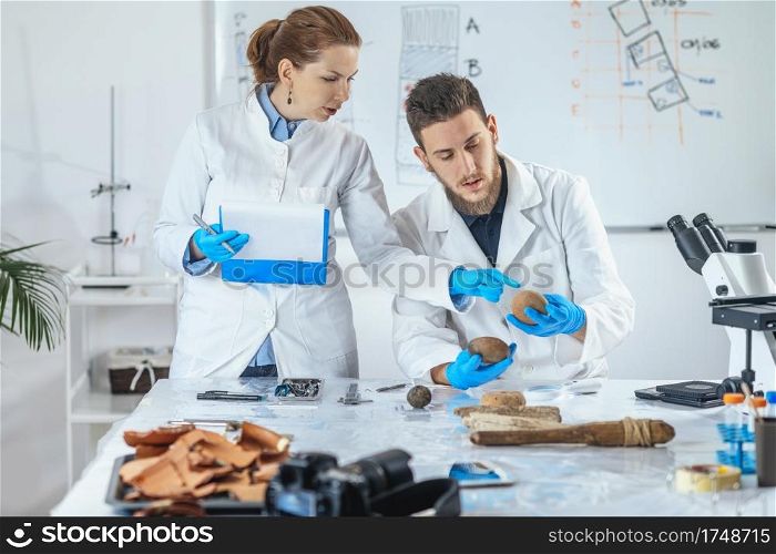Archaeologist analyzing ancient artifacts, loom weight or fishing net weight. . Archeology Scientists Analyzing Ancient Weight in Laboratory