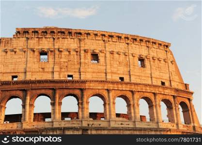 Arched antique facade of ancient architectural European landmark gladiatorial amphitheatre Colosseum in Rome Italy on the blue sky background