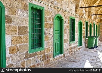 Arched gallery of mosque viewed from paved courtyard. Doors and windows in the old city of Akko in Israel.