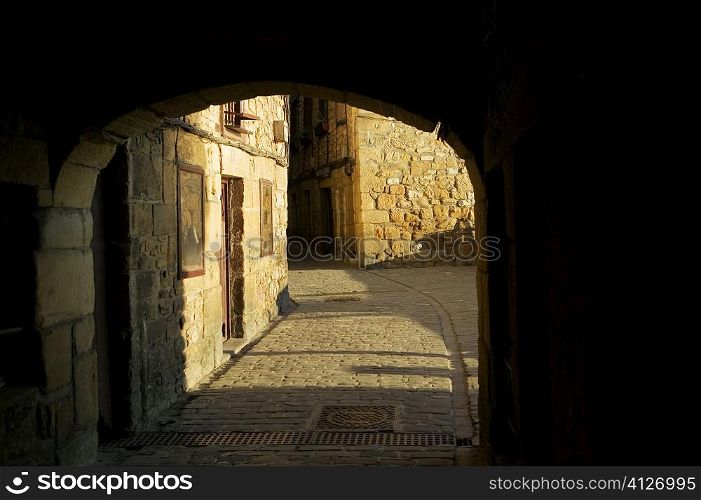 Arched gateway leading to a cobblestone alley, Spain