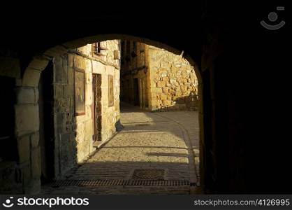 Arched gateway leading to a cobblestone alley, Spain