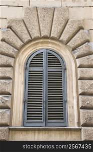 Arched window with closed shutters in Rome, Italy.